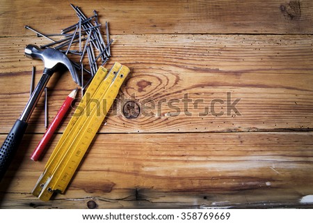 Nails, hammer,  pencil and folding meter on wooden background
