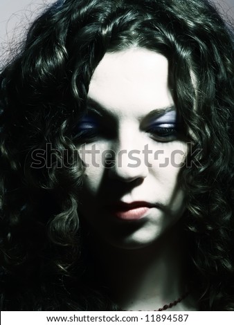 A low-key portrait about a pretty lady with white skin, long brown wavy hair and soft makeup