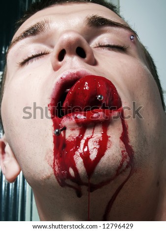A portrait about an attractive guy whose mouth is bleeding and he is licking his own blood.
