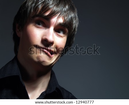 A portrait about a trendy attractive guy who is looking towards and he is moping. He is wearing a stylish black shirt.