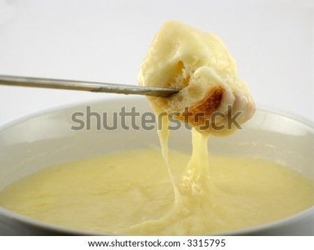 Melted cheese drips in strings from a chunk of fresh bread in cheese fondue dinner.