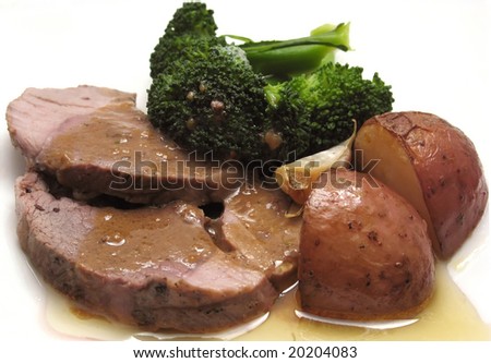 Roast lamb slices with broccoli, roasted potatoes and gravy.