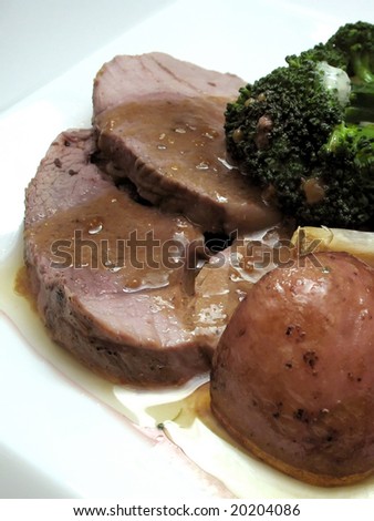 Roasted slices of lamb with roasted red potatoes, broccoli, gravy and garlic