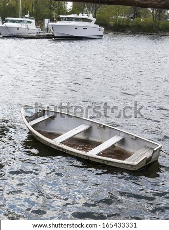Small sinking boat with water inside of a beautiful modern boats.