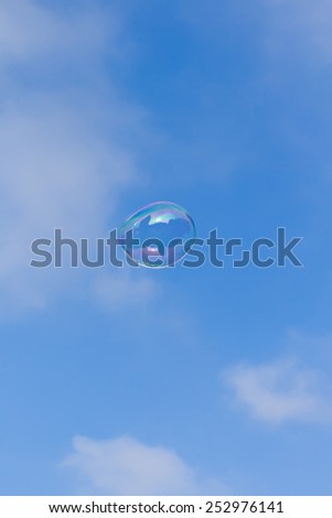 Soap bubble on the background of blue sky with white clouds