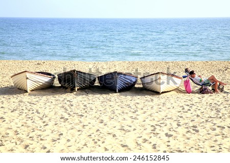 BOURNEMOUTH, DORSET,UK.-SEPTEMBER 2014. A couple relax on the beach by the side of a line of rowboats.