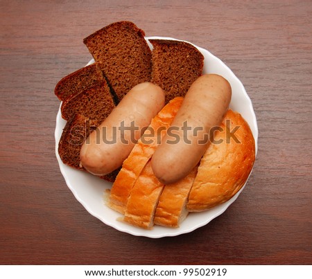 Bread, sausage in a plate on a wooden table