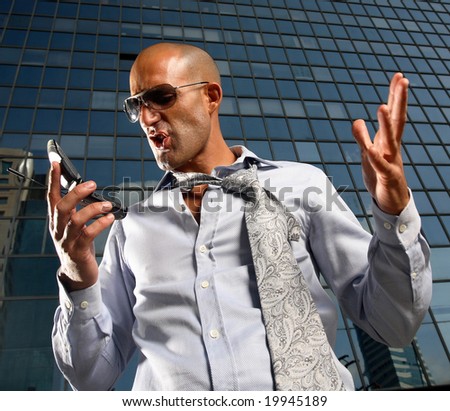 Worried, frustrated, freaked-out business man yelling at a cell phone on a business building background.