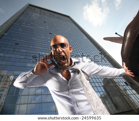 Worried, frustrated, freaked-out business man yelling at a cell phone on a business building background.