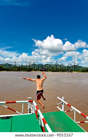 man jumping off river raft into water