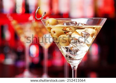 Several glasses of famous cocktail Martini, shot at a bar with shallow depth of field. The cocktail is made from 55 ml gin,15 ml dry vermouth,olives to garnish