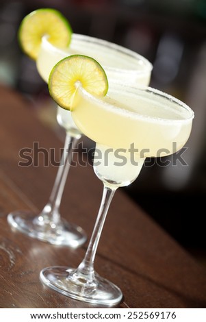 Two margarita cocktails on a bar