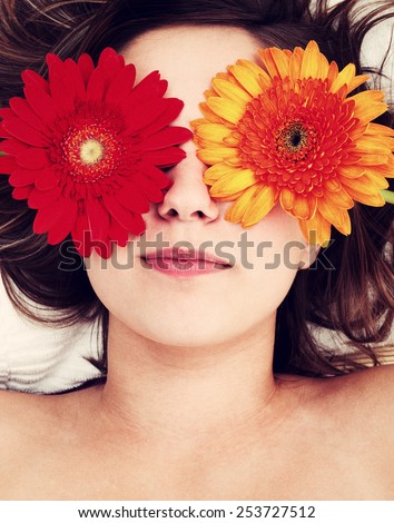 Young woman lying on white background with flowers in her hair waiting in spa studio for massage