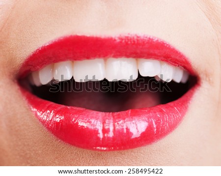 Attractive woman lips in toothy smile with red lipstick, close up