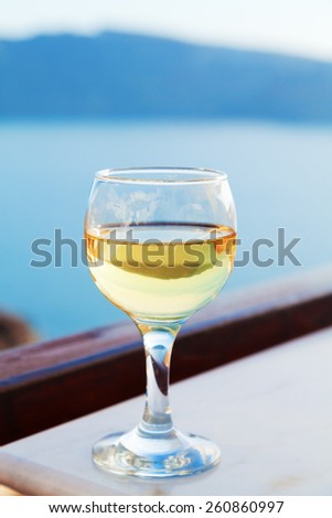 A single glass of white wine on a table in a summer resort with a perfect view to the volcano