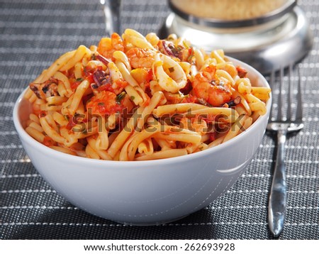 Pasta with seafood and tomato sauce, one portion on the table with glass of wine