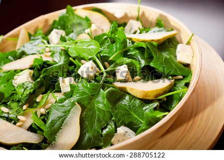Fresh spinach salad with blue cheese, pears and honey served in a salad bowl, close up