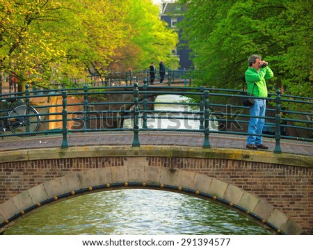 Amsterdam, Netherlands, The - May 02, 2008 : Middle aged man shooting with camera on a small bridge in Amsterdam