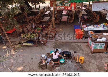 Mandalay, Myanmar - February 27, 2011 : Young Burmese woman sitting on the street and selling food near Mandalay
