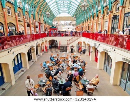 London, United Kingdom - April 21, 2012 : Covent Garden enclosed market with cafes and restaurants with a lot of shopping people inside, sometimes there are street musicians and other performers