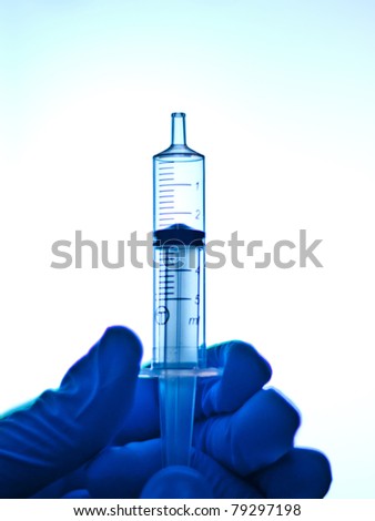 Medical hands inspecting a syringe before attaching the needle.