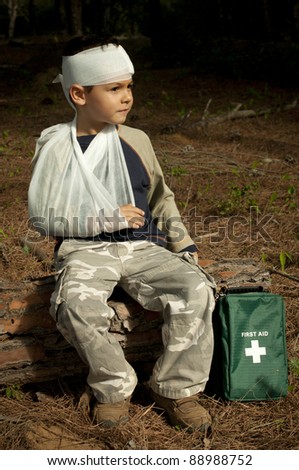 First Aid treatment given to a young boy in the forest, showing an arm sling and a head injury.