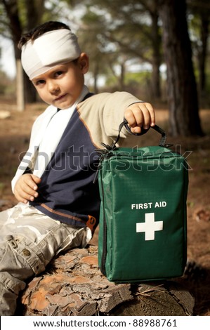 First Aid treatment given to a young boy in the forest, showing an arm sling and a head injury.