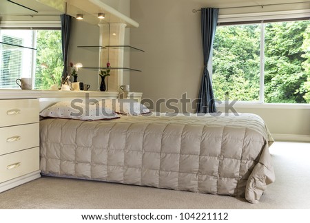 Master bedroom with king size bed, large mirror and open curtains showing green trees in background