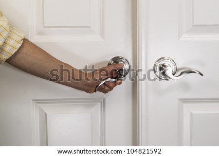 Hand pulling down chrome door handle on white panel door