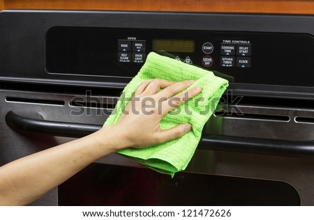 Hand with microfiber cleaning rag wiping outside of electric oven