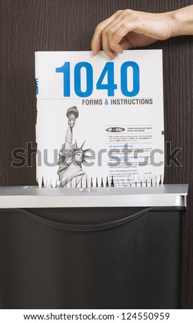 Female hand placing personal income tax form cover page into paper shredder