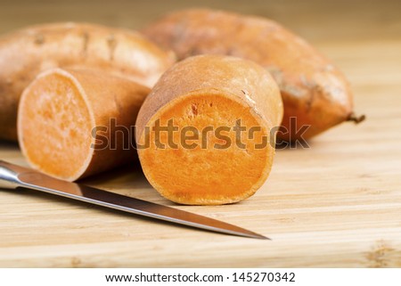 Horizontal photo of sliced yam potato, knife and bamboo cutting board