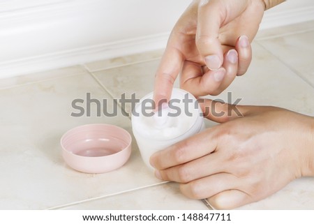 Close up horizontal photo of female hands dipping index finger into cosmetic cream
