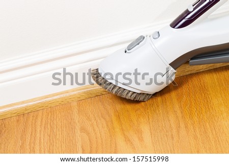 Horizontal photo of vacuum cleaner brush extension cleaning floor and trim work