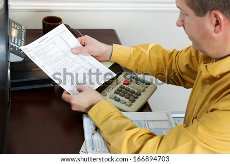 Horizontal photo of mature man pulling, with focus on tax worksheet, tax forms from printer