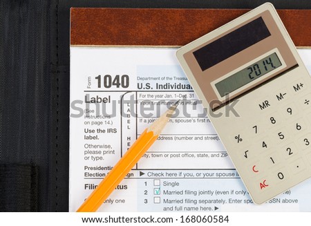 Horizontal photo of United States Tax Form 1040, for Individual Income, with Calculator and pencil on nylon business folder