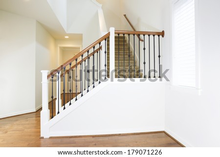 Horizontal photo of residential hard wooden floors and custom staircase made of iron and wood railing with carpet on steps