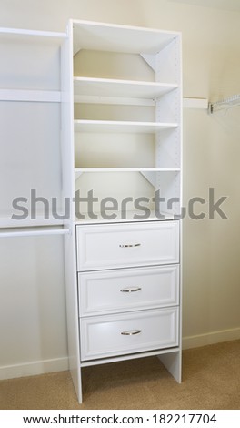 Vertical photo of modern white shelf inside of master bedroom closet residing on carpet