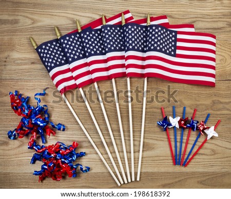 Overhead view of United States of America flags, ribbons and pinwheels positioned on rustic wooden boards.