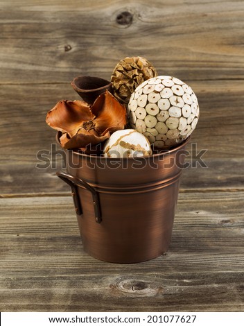 Vertical photo of home decorations place inside of a copper metal bucket on rustic wood