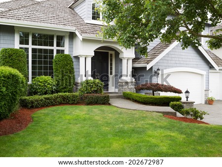Newly painted exterior of a North American home during summertime with green grass and flower beds