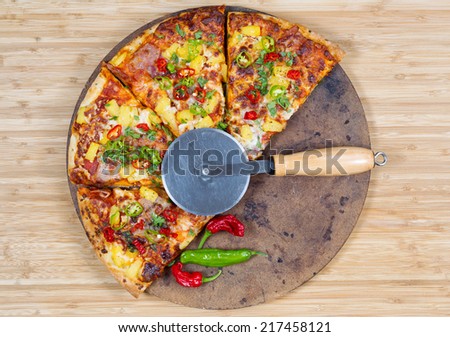 Top view of a freshly baked pizza with cutter on stone and natural bamboo board