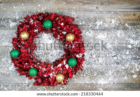 Top view of wreath consisting of real tree leaves and Christmas ornaments with snow on rustic wood