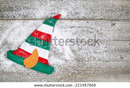Horizontal image of Christmas elf stocking hat on rustic wooden boards covered with snow