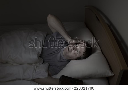 Mature man, looking up at ceiling, having trouble falling asleep at night from insomnia