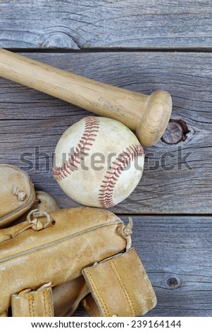 Vertical image of a partial old worn glove, bat and used baseball on rustic wood