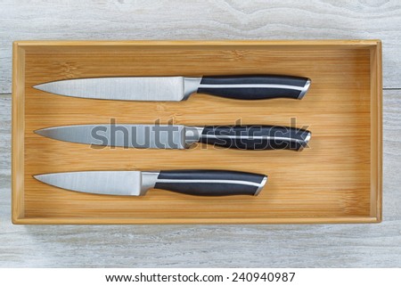 Close up horizontal image of a new wooden kitchen drawer with knife set resting on rustic white wood