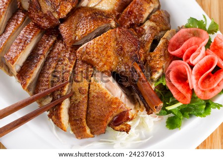 Top view of Chinese crispy roasted duck in white plate with natural bamboo background