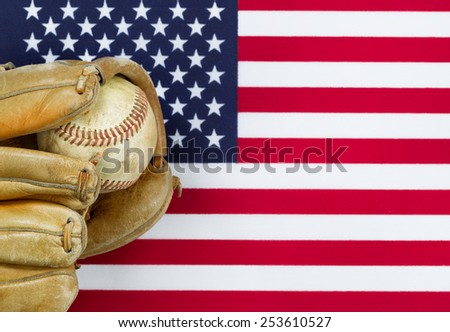 Close up image of worn leather mitt and used baseball with United States of America flag in background. Concept of baseball sport in America.