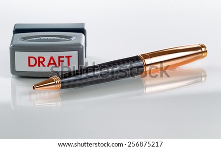 Elegant business pen and draft stamp, focus on part of pen front and stamper, in background on glass with white background